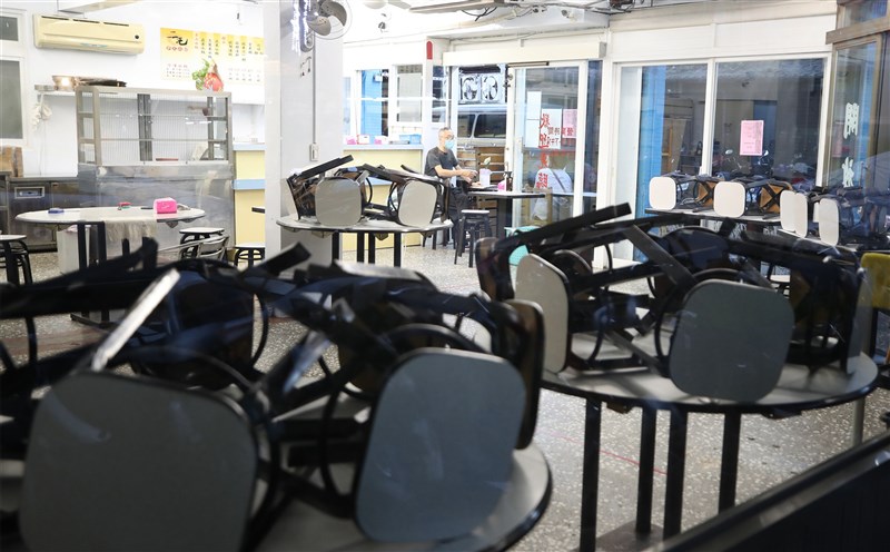 7月27日全國疫情警戒降為二級，但疫情相對嚴峻的雙北地區仍禁止餐廳內用，台北一家麵店把椅子疊在桌面上，老闆在門口接受點餐。