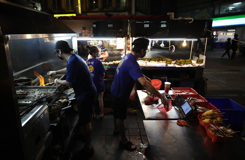 台北寧夏夜市「微解封」，迎接準備外帶美食的民眾，攤商忙著準備食材。