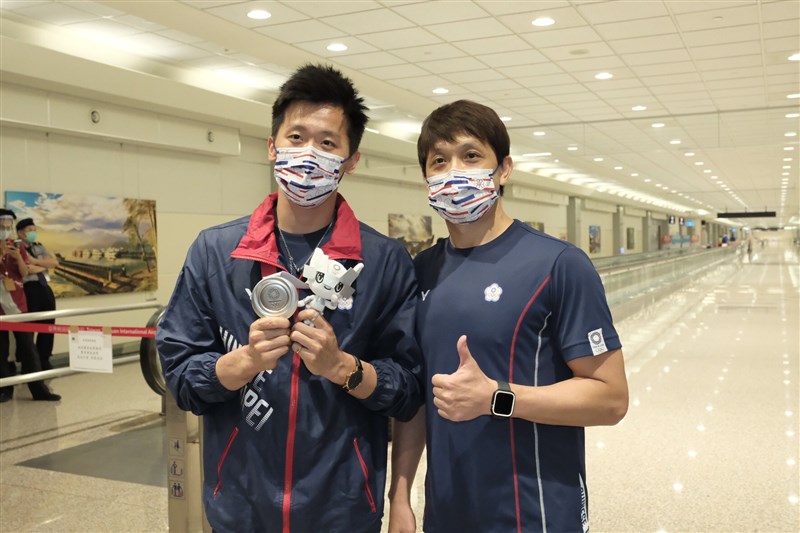 拿下東京奧運男子鞍馬單項決賽銀牌的體操選手李智凱(左)3日與教練林育信(右)返台,李智凱下機秀出台灣體操史上首面奧運獎牌。中央社記者吳睿騏攝 110年8月3日