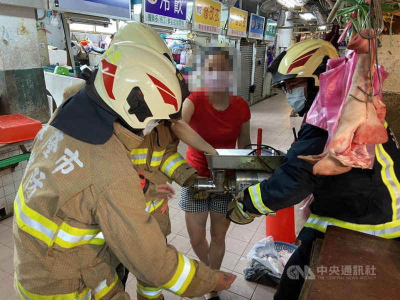 基隆市范姓女子(紅衣)4日上午在信義市場豬肉攤操作絞肉機時不慎將手捲入機器內,消防員到場連人帶機送醫,所幸范女僅右手中指第一節受有撕裂傷,已安排縫合傷口,不需住院治療。(讀者提供)中央社記者王朝鈺傳真 110年8月4日