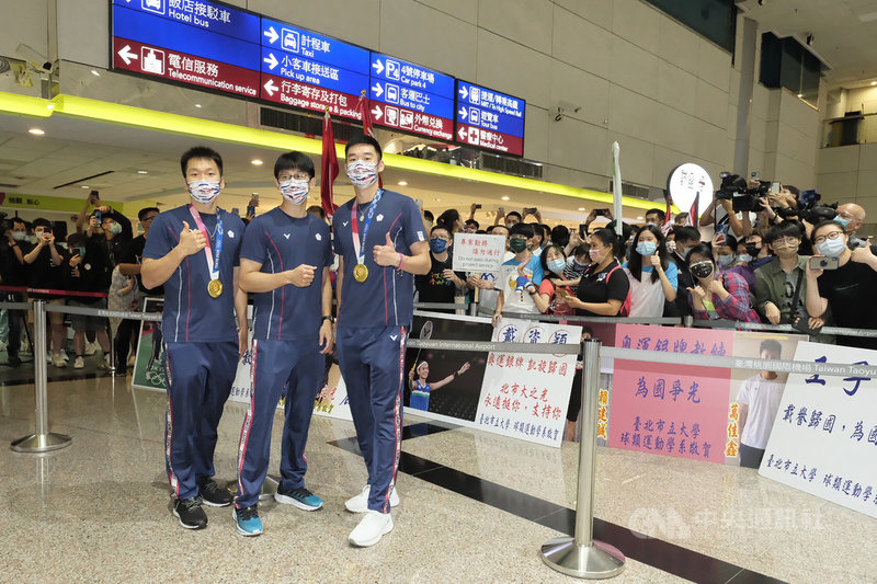 台灣羽球男雙組合「麟洋配」王齊麟（前右）和李洋（前左）在東京奧運勇奪金牌，兩人與教練陳宏麟（前中）4日搭機返台，開心和前來接機的支持者們合影。中央社記者吳睿騏桃園機場攝　110年8月4日