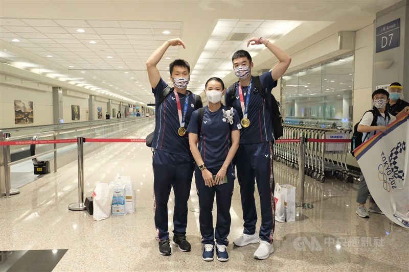參加東京奧運的台灣羽球代表隊的教練及選手們4日返台,受到熱烈歡迎。其中拿下羽球男子雙打金牌的王齊麟(右)、李洋(左),與羽球女子單打銀牌戴資穎(中),更是大家矚目的焦點。中央社記者吳睿騏桃園機場攝 110年8月4日
