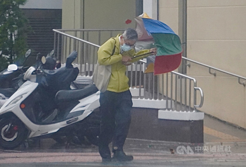 中央氣象局表示,5日受颱風外圍環流影響,中南部地區有陣雨或雷雨,並有局部大雨或豪雨發生的機率。高雄有民眾在強風陣雨中行走時,傘差點開花。中央社記者董俊志攝 110年8月5日