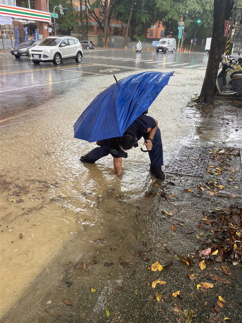 今天上午9時許，高雄市左營區文慈路與重愛路口被巡邏員警發現慢車道積水，員警徒手伸入積水，挖開樹枝、樹葉疏通排水孔。（高雄市警察局左營分局提供）中央社記者蔡孟妤傳真 110年8月14日