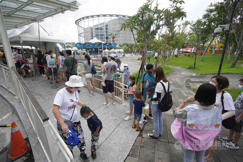 國內COVID-19疫情趨緩,台北市政府日前宣布動物園、天文館、兒童新樂園等入園人數上限將逐步放寬,兒童新樂園每日預約人數提升至2400人,15日預約額滿,家長帶著小孩開心在遊樂設施排隊等候。中央社記者徐肇昌攝 110年8月15日