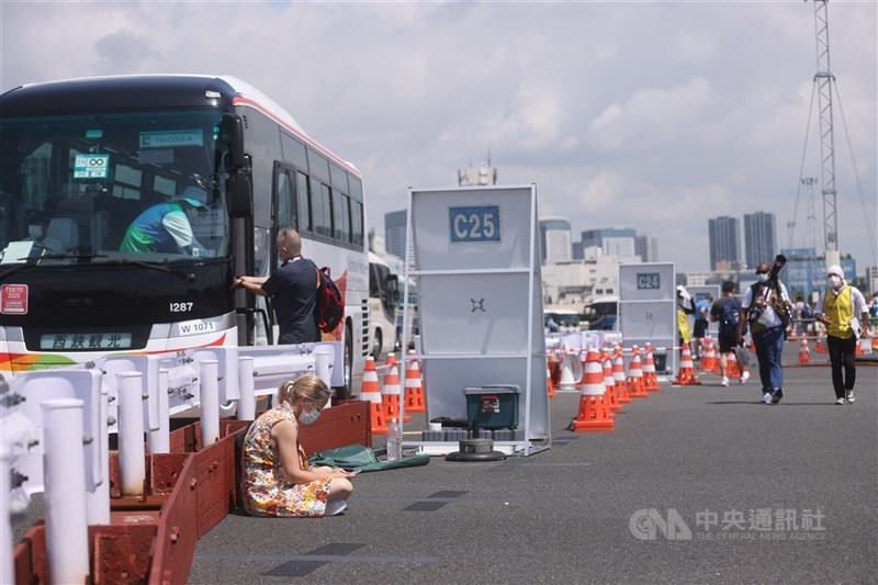 烈日下邊等車邊工作的記者，錯過接駁車的話，就要再等一小時。