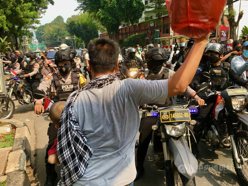 滯留印尼的阿富汗難民24日要求聯合國難民署儘速安置,印尼警方強制驅離,一名難民不顧一切,抱著小孩要阻擋警方前進。中央社雅加達攝 110年8月25日