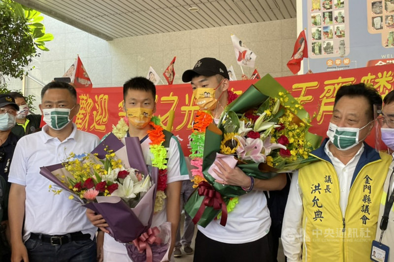 出身金門的東京奧運羽球男雙金牌李洋(前左2)返鄉,29日上午與搭檔王齊麟(前左3)搭乘華信班機抵達金門尚義機場,受到民眾英雄式歡迎,隨後準備搭車繞行市區。前左為金門縣長楊鎮浯。中央社記者黃慧敏攝 110年8月29日