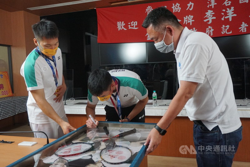 為金門奪得首面奧運金牌的李洋(左)29日返回家鄉金門,搭檔王齊麟(中)同行,兩人下午在縣府直播記者會中贈送紀念球拍給縣長楊鎮浯(右)。中央社記者黃慧敏攝 110年8月29日