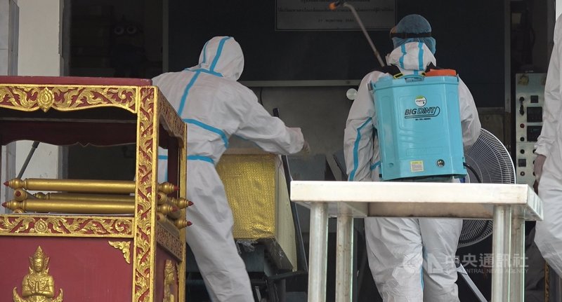泰國第三波疫情嚴峻,8月中旬以來死亡人數每日新增破200人,寺廟協助火化死者屍體,圖為工作人員做火化前的最後準備工作,另一人則在一旁灑消毒水。中央社記者呂欣憓曼谷攝 110年8月31日