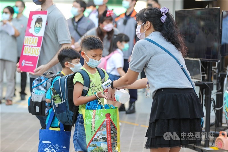 指揮中心1日宣布，新增1例本土、5例境外移入及1例死亡病例。圖為開學首日老師在幫學生消毒。中央社記者黃旭昇新北攝 110年9月1日