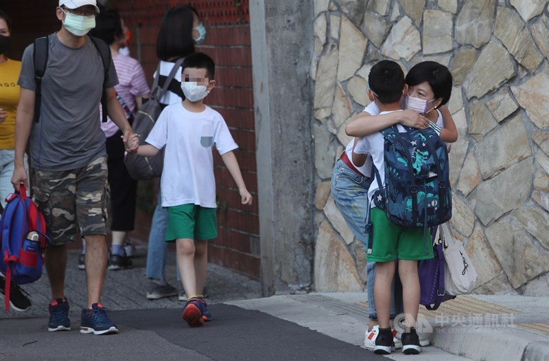 新北市幼兒園群聚案延燒,因應Delta病毒入侵,新北多所學校預防性停課,將環境內外徹底消毒,確保師生安全。圖為10日板橋區一所國小復課,小朋友在校門外與家長擁抱。中央社記者吳家昇攝 110年9月10日