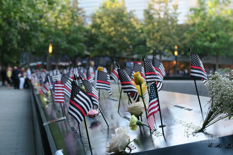 911恐怖攻擊事件20週年,紐約世界貿易中心雙塔遺址刻有罹難者姓名的紀念水池插滿鮮花與小型星條旗。中央社記者尹俊傑紐約攝 110年9月12日
