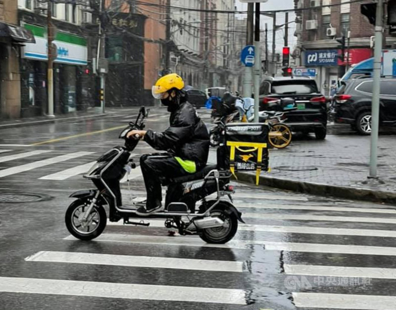 颱風璨樹(中國大陸稱燦都)為上海帶來風雨,不少人選擇叫外送解決吃的問題。雖然路上外送員明顯減少,但仍有人把握賺錢機會。圖為冒著風雨送餐的美團外送員。中央社記者吳柏緯上海攝 110年9月13日