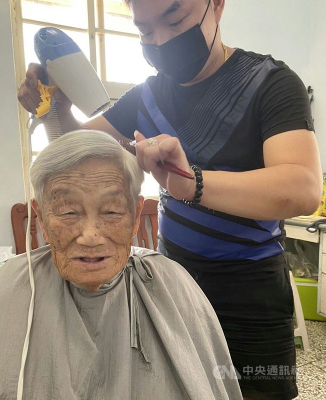 34歲的陳邦輝(右)每年都會利用暑假或中秋期間返澎省親,他19日搭船到澎湖後,20日先由沙港老家展開義剪,透露長輩理髮後,得讓他們拿著鏡子檢視一番,要長輩感到滿意才算完成。中央社 110年9月20日