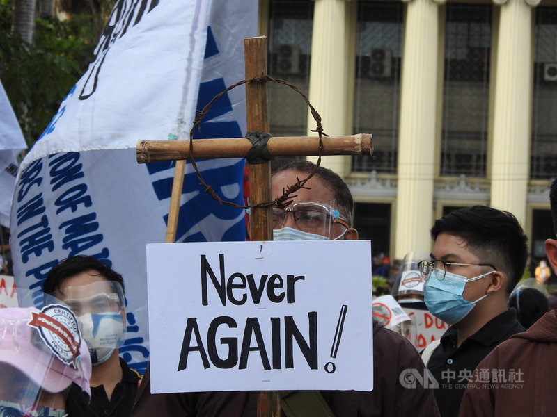 數千名菲國民眾21日集結馬尼拉市波尼法西奧廣場示威，民眾手持寫著「（戒嚴）永不重來」的十字架，呼籲別再讓杜特蒂和馬可仕家族2022年延續政治影響力。中央社記者陳妍君馬尼拉攝  110年9月21日