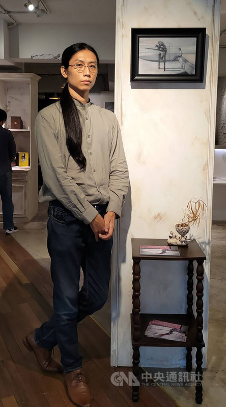 畫家曾耀慶以夢境為靈感,創作多幅以叩問自我為核心的畫作,集結為「懸浮狀態-曾耀慶個展」,21日在分享會中更形容個展畫作就如「與自我對話的過程」。圖為曾耀慶與作品「界線裡的風景」合影。中央社記者王寶兒攝 110年9月21日