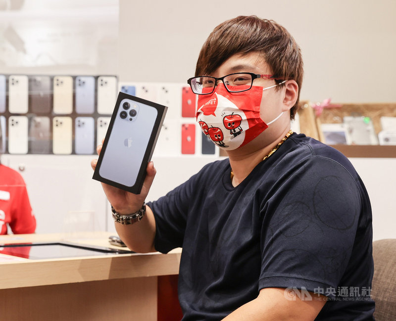 蘋果iPhone 13系列新機24日開賣,電信三雄照例於信義威秀門市舉辦首賣,民眾劉先生23日就來遠傳電信排隊,搶得頭香,秀出剛拿到的新手機。中央社記者鄭清元攝 110年9月24日