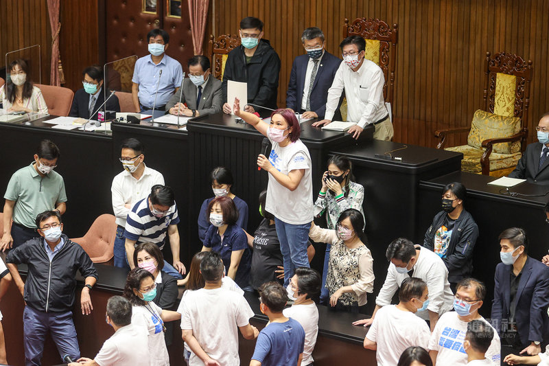 立法院院會28日上午在藍綠激烈衝突下導致議事停擺,下午宣布繼續開會後,國民黨立院黨團書記長陳玉珍(中持麥克風者)站上桌發言,朝野立委包圍在旁嚴陣以待。中央社記者鄭清元攝 110年9月28日