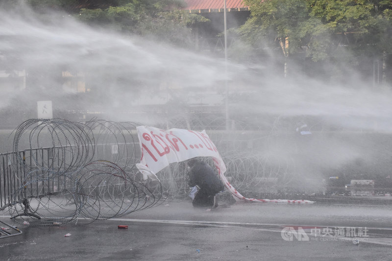 泰國反政府示威人士28日在靠近總理府的楠稜路口(Nang Leong Junction)遭到警方以水砲車驅離,抗議民眾尋找遮蔽物。中央社記者呂欣憓曼谷攝 110年9月28日