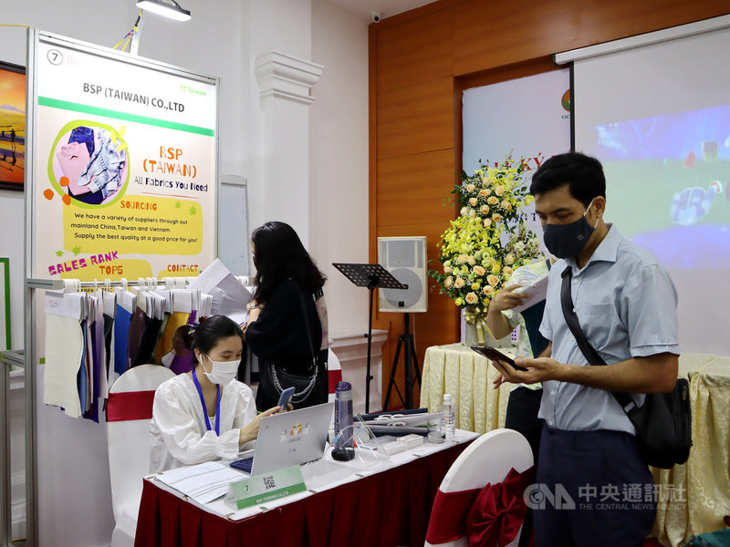 越南自COVID-19疫情中逐步恢復,台灣紡織業者相中疫後復工潮,透過線上參與在河內市舉行的紡織品展示會。圖為越南買主到場鑑賞,並由翻譯人員協助在線上對接。中央社記者陳家倫河內攝 110年10月7日