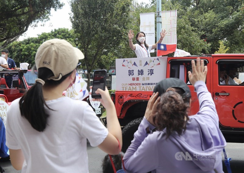 「OUR HEROES!台灣英雄大遊行」10日在國慶典禮後登場,民眾聚集在遊行路線熱烈歡迎,舉重選手郭婞淳(後)在車隊上跟民眾打招呼。中央社記者張皓安攝 110年10月10日