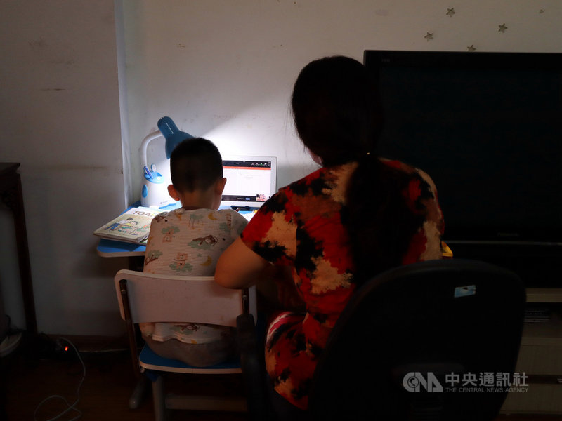 因為COVID-19疫情,越南的小學生2021年幾乎都在家線上學習,家長在工作之餘又要花時間陪小孩上課,長久下來疲憊不堪。圖為正在陪課的越南家長。中央社記者陳家倫河內攝 110年10月13日