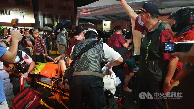 高雄鹽埕區「城中城」大樓14日凌晨發生大火。圖為消防人員出動雲梯車救出一名老婦和其家人送醫。中央社記者洪學廣攝110年10月14日