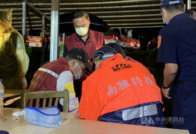 雙北地區多位家長與學生16日到新北市虎豹潭一帶參加自然體驗營,午後遇大雨折返途中有多人落水,晚間仍有6人失聯,現場全力搜救中,新北市長侯友宜(坐者左)晚間趕赴現場了解狀況。中央社記者沈佩瑤攝 110年10月16日