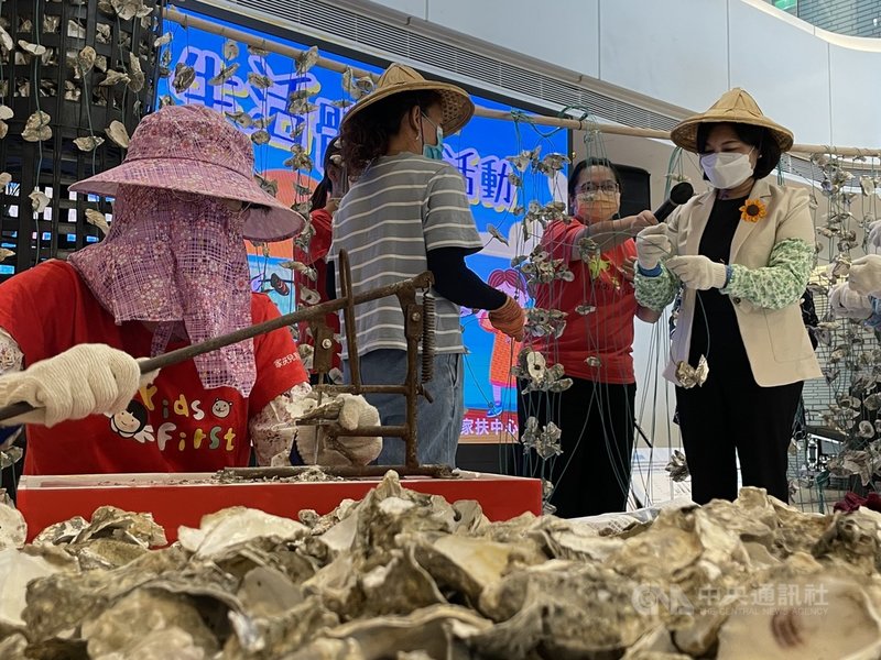 雲林縣長張麗善(右)18日在家扶媽媽引導下戴上工作手套,將蚵殼打洞串綁起來,體驗串蚵工生活,呼籲民眾關心偏遠鄉鎮弱勢經濟家庭。中央社記者姜宜菁攝 110年10月18日