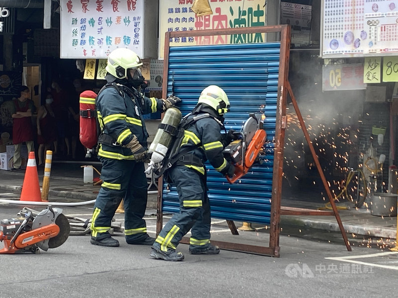 為避免高雄城中城大樓火警憾事重演,台北市消防局21日針對建齡50年的信維大樓進行消防搶救演練,情境設定1樓攤商因煮食不慎而引發火災,大火竄升、濃煙密佈,消防人員使用工具鋸門,以搶救受困屋內、樓梯間和屋頂上的住戶,場面逼真。中央社記者黃麗芸攝 110年10月21日