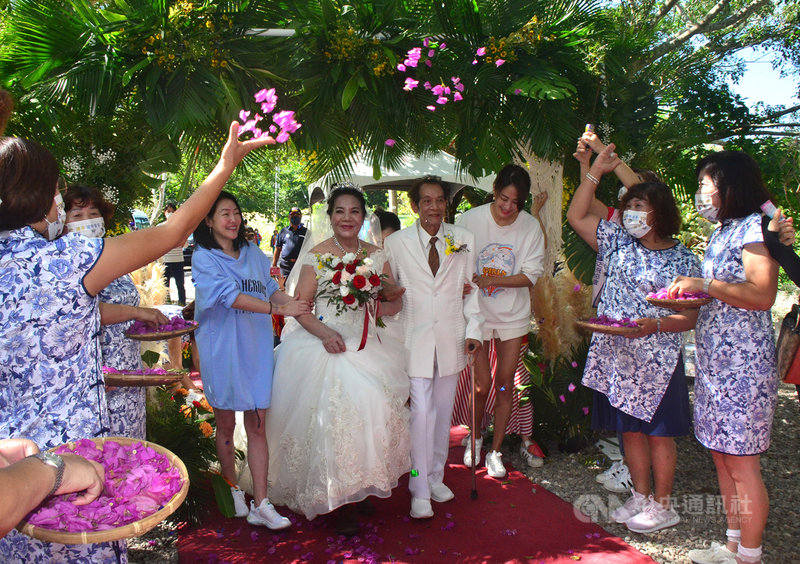 台東72歲高春惠(右5)結婚時未披婚紗,21日在社福團體幫忙下穿上白紗,挽著丈夫黃阿財(右4)的手,在藝人賈永婕(右3)和小S(徐熙娣)(右6)陪同下走紅地毯。中央社記者盧太城台東攝 110年10月21日