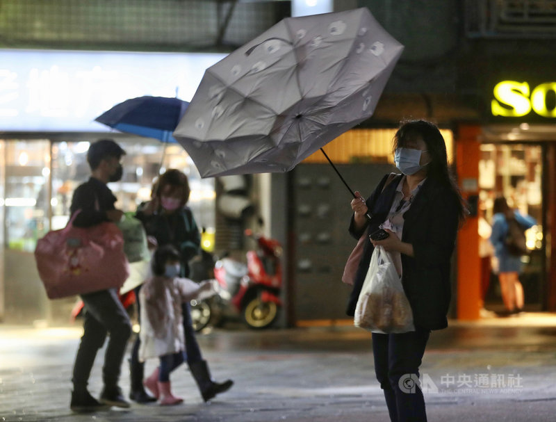 中央氣象局表示,週末天氣將與22日類似,北台灣持續有降雨,溫度落在攝氏18度到19度之間,提醒外出民眾留意保暖、帶雨具。圖為22日晚間民眾的傘被風吹得開花。中央社記者張皓安攝 110年10月22日