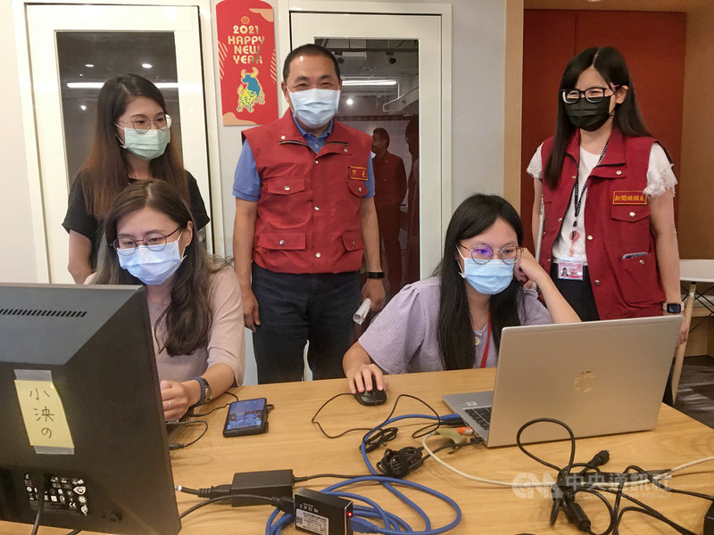 新北市政府27日表示,自媒體已成為官方宣導市政的主流,臉書「我的新北市」粉絲頁粉絲人數即將突破百萬大關。市長侯友宜(後中)與新聞局長張愛晶(後右)9月24日在疫情記者會後,慰問線上直播的影音小組成員。中央社記者黃旭昇新北攝 110年10月27日