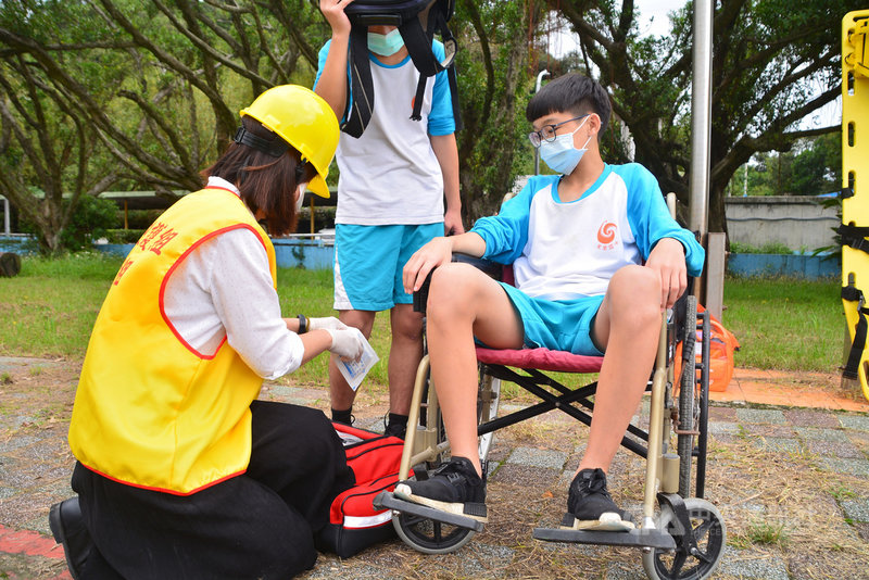 新北市萬里國中28日實施地震防災演練,讓師生熟悉應變與逃生動線。演練模擬有學生受傷,學校護理師陳怡芬(前左)在救護站檢視傷口後給予包紮。中央社記者黃旭昇新北攝 110年10月28日