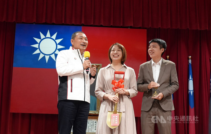準新郎銀行員劉紘君(右)機警察覺婦人疑遭詐騙,成功攔阻獲表揚,新北市侯友宜(左)9日送上金鏟子,允諾若催生成功,一定送大禮。中央社記者沈佩瑤攝 110年11月9日