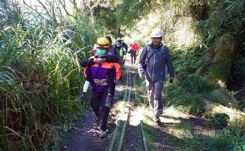 阿里山林鐵眠月線第2號隧道崩塌處17日發生1名女性山友不慎摔傷,右腳踝骨折,救援人員揹著傷者下山。(嘉義林管處提供)中央社記者黃國芳傳真 110年11月17日
