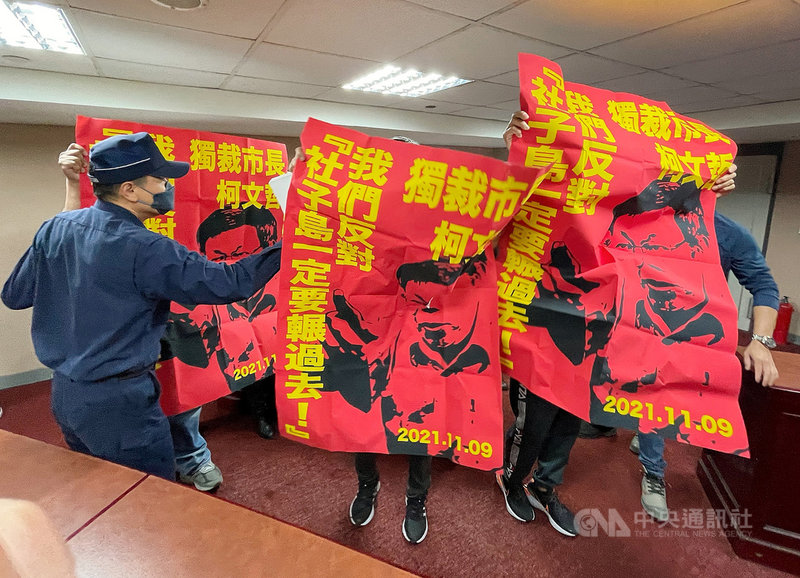 台北市長柯文哲19日列席台北市議會市政總質詢,不過突然有社子島自救會成員闖進位於3樓的記者旁聽席,高舉海報、喊口號向議場內的柯文哲表達抗議,警衛上前處理,雙方一度拉扯衝突。中央社記者郭日曉攝 110年11月19日