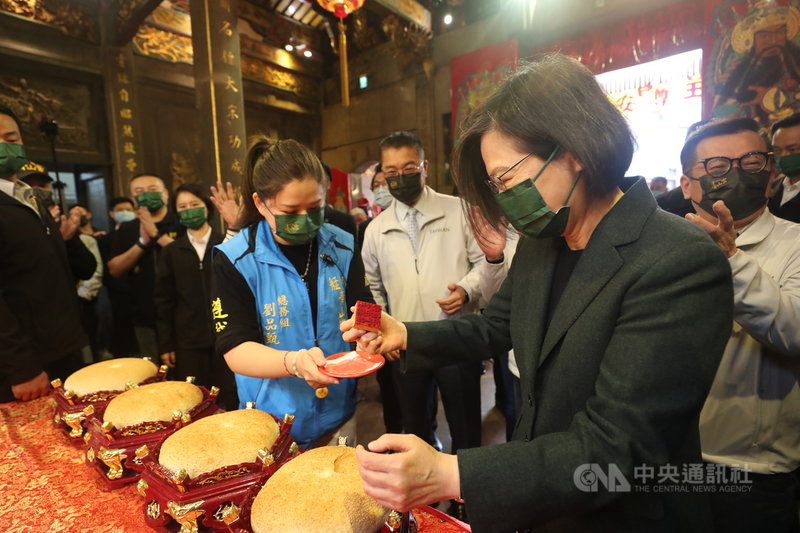 總統蔡英文(前右)26日上午出席「艋舺青山王祭起駕儀式」,將青山宮紅印蓋上大餅。中央社記者吳家昇攝 110年11月26日