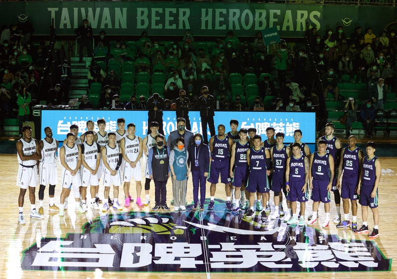 T1聯盟元年開幕戰27日晚間在天母體育館點燃戰火,台啤英熊隊(左白衣)在主場迎戰高雄全家海神隊(右藍衣),賽前球員和與會貴賓們合影。中央社記者謝佳璋攝 110年11月27日