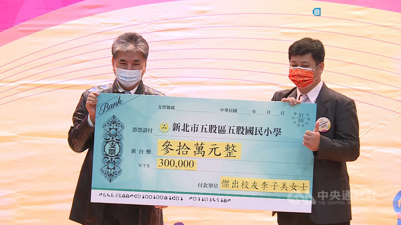 新北市五股國小27日歡慶百年校慶,前內政部長李鴻源(左)代表獲頒傑出校友的母親李子美捐贈新台幣30萬元圖書經費,由校長曾進發(右)代為接受。(五股國小提供)中央社記者黃旭昇新北市傳真 110年11月27日