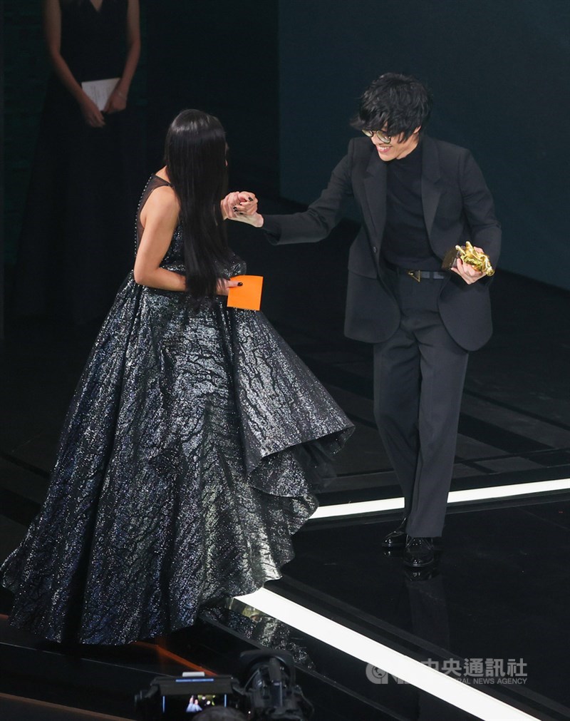 歌手艾怡良(左)包辦詞曲創作及演唱的歌曲「我這個人」,成功拿下本屆金馬獎最佳電影原創歌曲,頒獎人盧廣仲(右)貼心上前攙扶艾怡良上台領獎。中央社記者鄭清元攝 110年11月27日