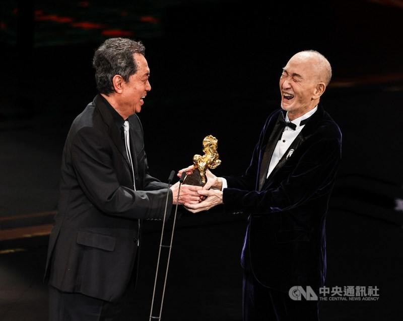 導演朱延平(左)頒發第58屆金馬獎終身成就獎給82歲資深導演蔡揚名(右),蔡揚名抱著獎座面露燦爛笑容,直呼自己是「太幸運」,金馬獎肯定他60幾年來的成就。中央社記者鄭清元攝 110年11月27日