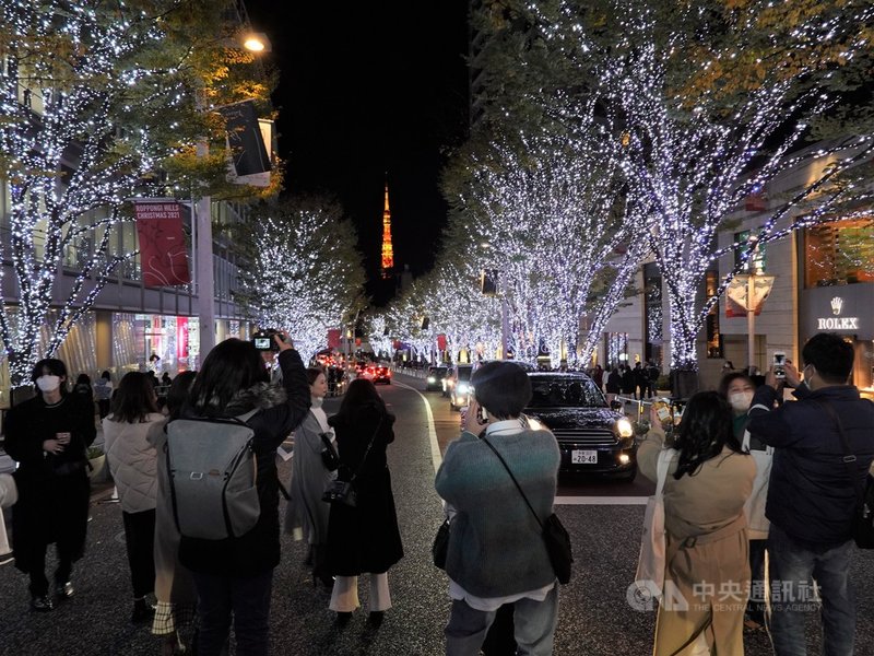 東京六本木Hills的六本木櫸坂通耶誕彩燈活動,在400公尺路面兩旁路樹點綴著約70萬顆藍、白色燈光。很多年輕人在綠燈通行時,在馬路中間拍照,與東京鐵塔同框照。中央社記者楊明珠東京攝 110年11月28日