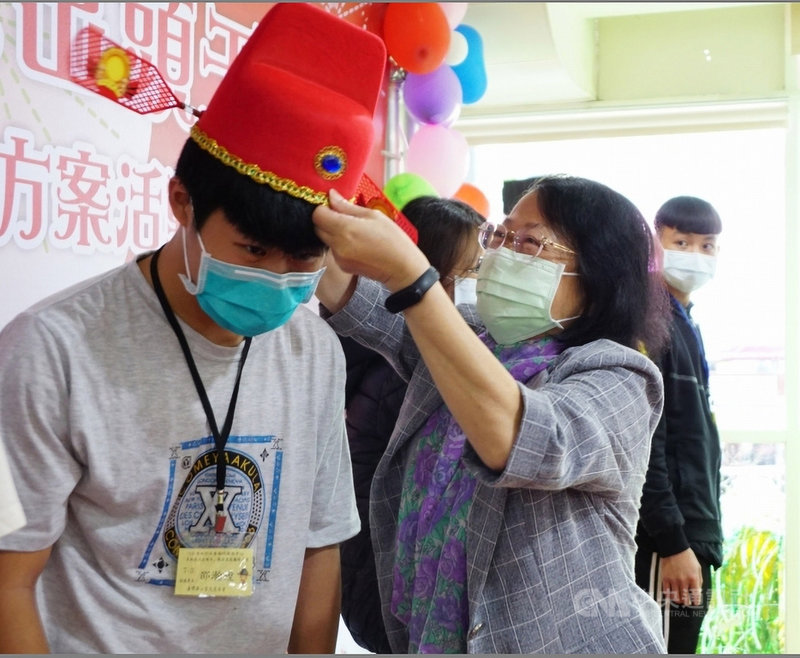 為讓弱勢家庭子女安心就學,高雄市「草地狀元出頭天」助學金今年共嘉惠91戶逾128名學子,社會局長謝琍琍(右)替受助學子戴上狀元帽。(高雄市政府提供)中央社記者曾以寧傳真 110年11月28日