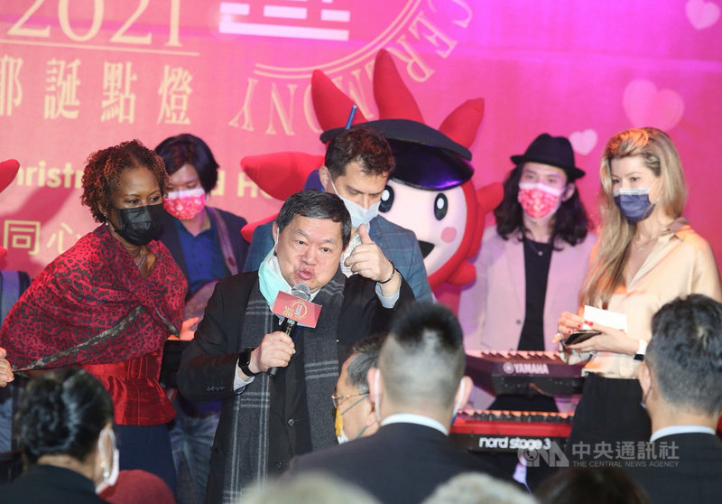 2021遠東集團耶誕點燈儀式29日晚間在遠企中心噴水池廣場舉行,遠東集團董事長徐旭東(中前)在台上歡唱歌曲,徐旭東之子、遠東集團創新長徐國安(中後)也攜手妻子徐佳莉(右)現身。中央社記者郭日曉攝 110年11月29日