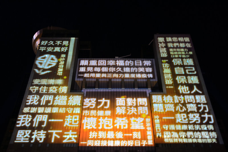 2021新北歡樂耶誕城活動3日正式點燈開城,新北市府除邀請防疫期間辛苦付出的醫護警消與民政人員共同點燈,也在市府大樓藉投影呼籲團結防疫、一起努力。中央社記者黃旭昇新北市攝 110年12月3日