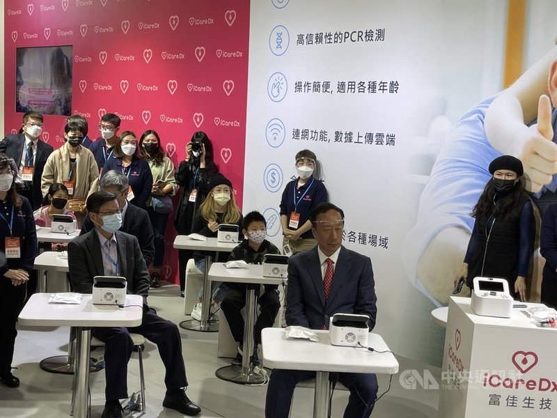 鴻海創辦人郭台銘(前右)4日出席醫療科技展,讚譽生策會會長翁啟惠(前左)為生技界貢獻,兩人一起示範俗稱「口水機」的專業版唾液PCR核酸檢測系統。中央社記者韓婷婷攝 110年12月4日