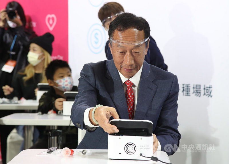 鴻海創辦人郭台銘(前)4日在台北南港展覽館一館出席2021台灣醫療科技展,為所投資的生技新創公司富佳生技站台,現場示範使用富佳生技所研發的PSS‐1s核酸檢測分析儀及試劑。中央社記者張新偉攝 110年12月4日