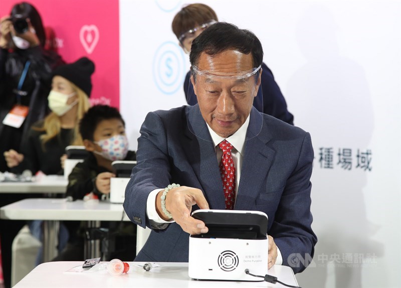 鴻海創辦人郭台銘(前)4日在台北南港展覽館一館出席2021台灣醫療科技展,為所投資的生技新創公司富佳生技站台,現場示範使用富佳生技所研發的PSS‐1s核酸檢測分析儀及試劑。中央社記者張新偉攝 110年12月4日
